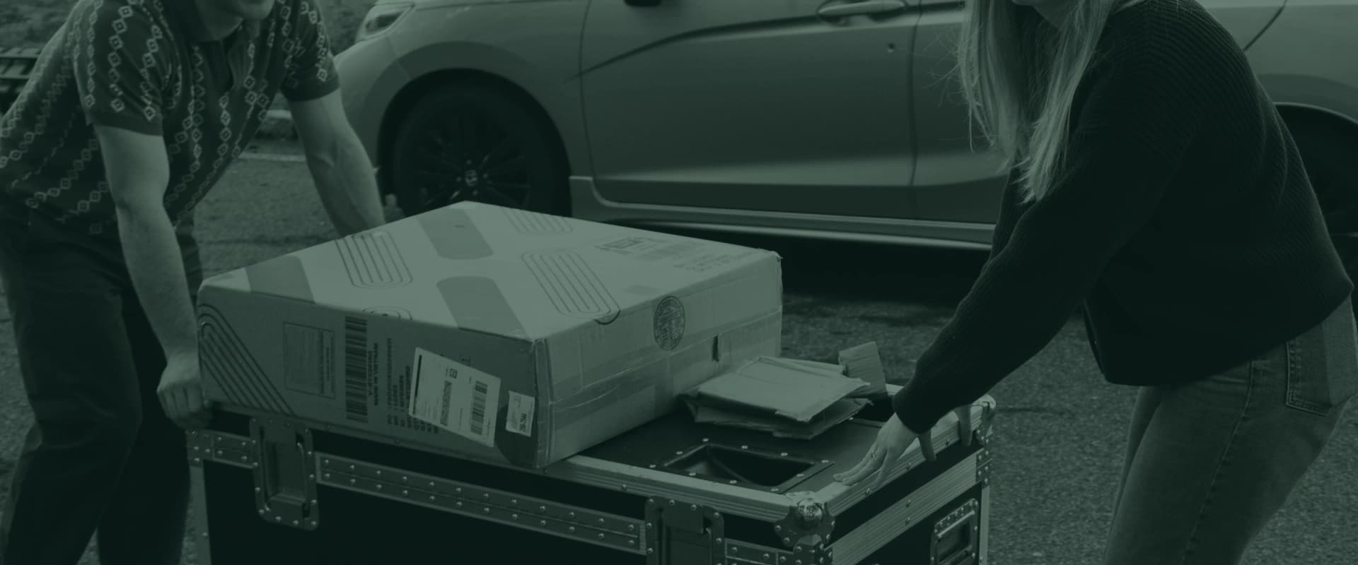 Two volunteers pushing a road case of equipment across the parking lot